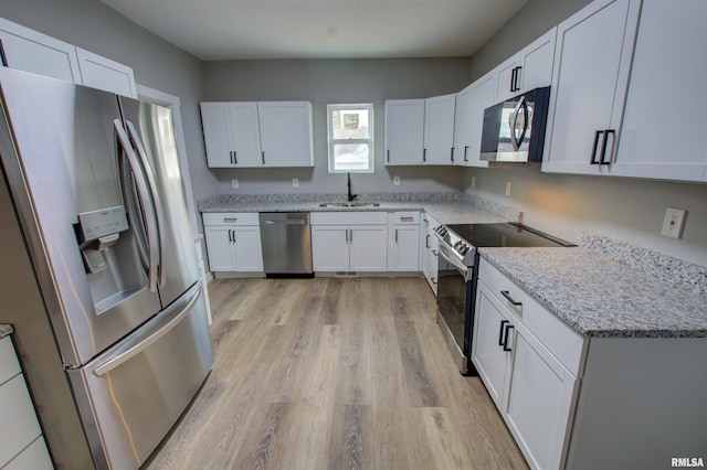 kitchen with sink, light hardwood / wood-style flooring, appliances with stainless steel finishes, light stone counters, and white cabinets