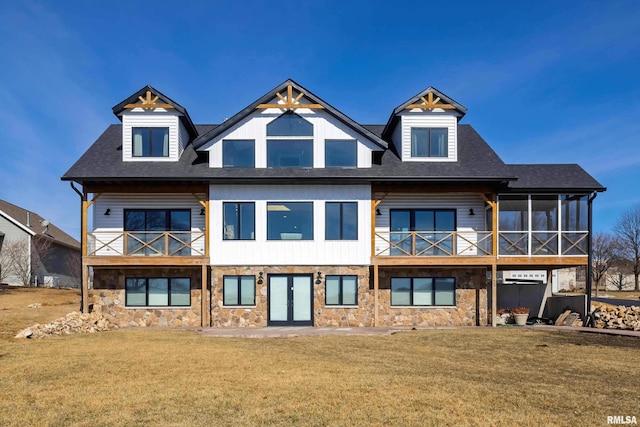 rear view of house with a sunroom, a lawn, a balcony, and french doors