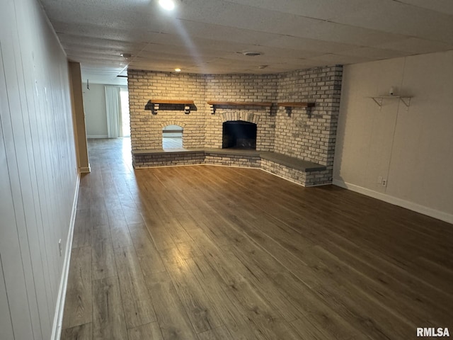 unfurnished living room with hardwood / wood-style floors and a brick fireplace