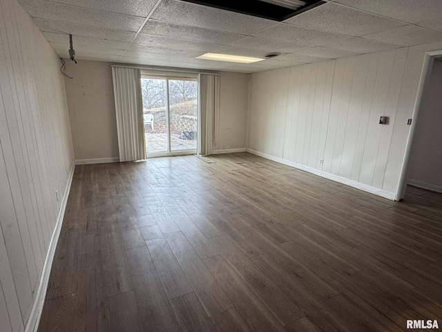 empty room with a paneled ceiling and dark hardwood / wood-style flooring