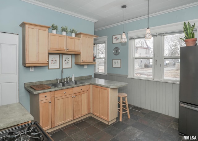 kitchen featuring light brown cabinetry, sink, decorative light fixtures, stainless steel refrigerator, and kitchen peninsula