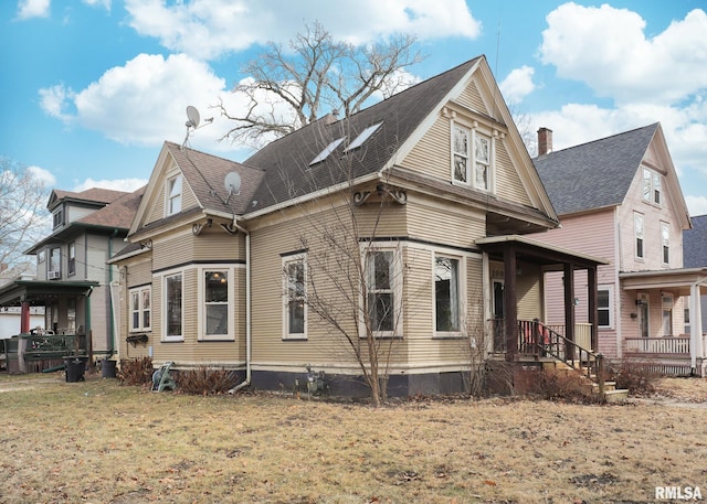 view of side of property with covered porch and a lawn