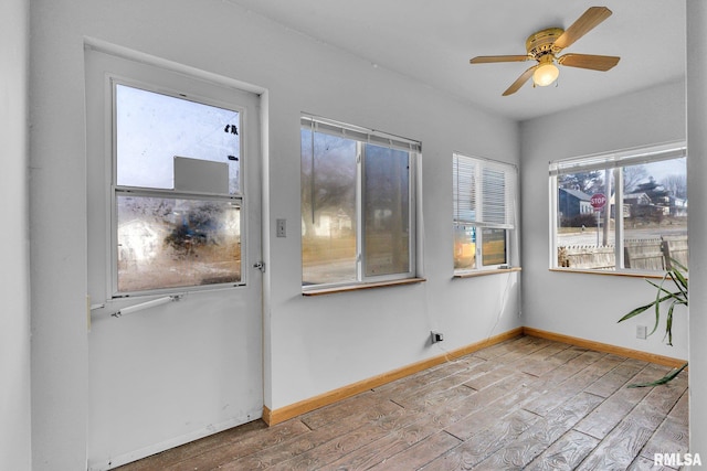 unfurnished sunroom featuring ceiling fan