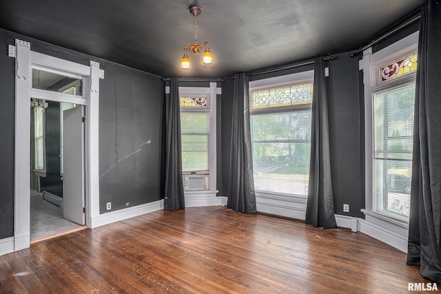 spare room featuring dark wood-type flooring, a wealth of natural light, a notable chandelier, and baseboard heating