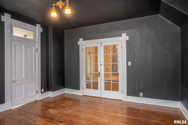 spare room featuring hardwood / wood-style flooring, a chandelier, and french doors