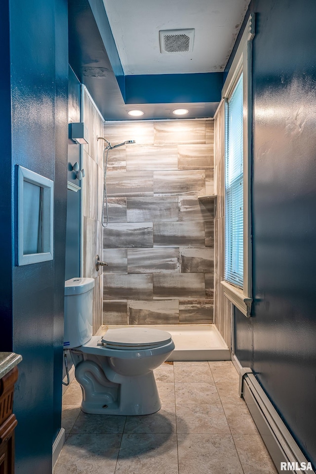 bathroom with tile patterned floors, toilet, a tile shower, and a baseboard heating unit