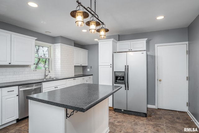 kitchen with sink, a center island, hanging light fixtures, stainless steel appliances, and white cabinets