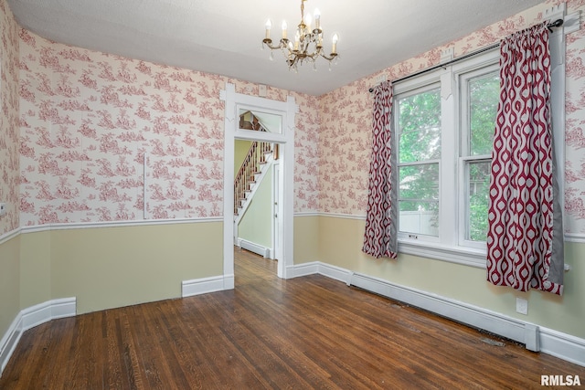 spare room with dark hardwood / wood-style flooring, an inviting chandelier, and baseboard heating