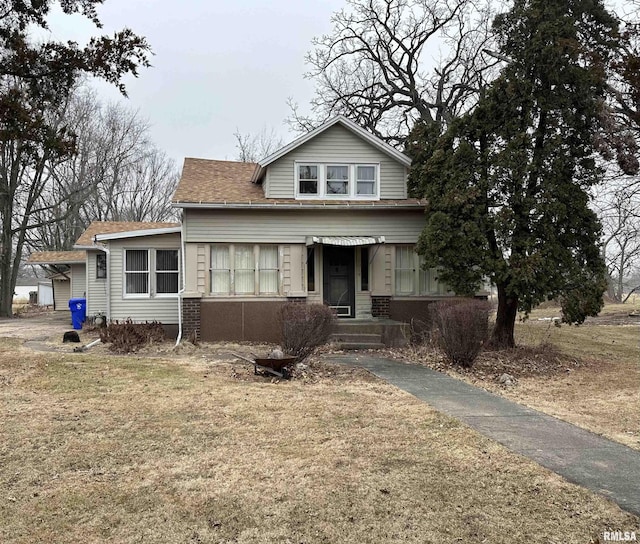 bungalow with a shingled roof and a front yard