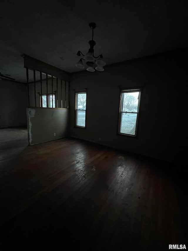 spare room featuring wood-type flooring, a chandelier, and a wealth of natural light