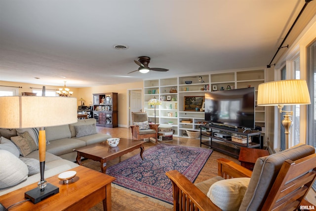 living room featuring wood-type flooring and ceiling fan with notable chandelier