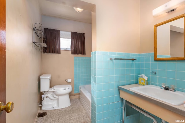 bathroom with tile walls, sink, toilet, and a tub to relax in