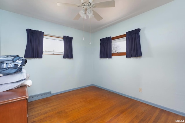 spare room featuring ceiling fan, hardwood / wood-style floors, and baseboard heating