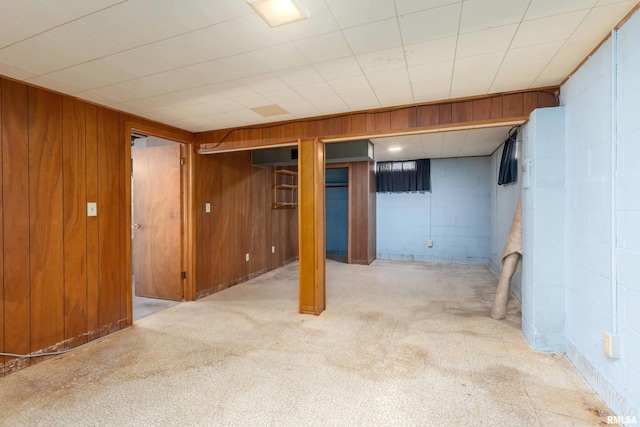 basement featuring wooden walls and light colored carpet