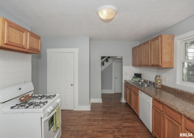 kitchen featuring sink, white appliances, dark wood-type flooring, dark stone countertops, and decorative backsplash