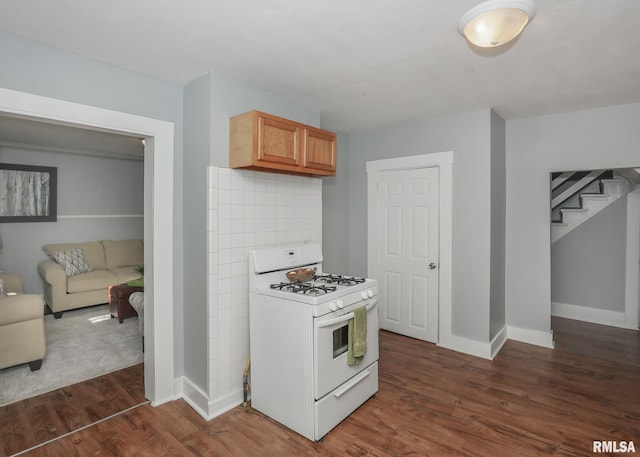 kitchen with dark hardwood / wood-style flooring, white gas stove, and decorative backsplash