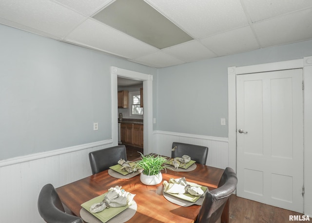 dining space featuring wood-type flooring and a drop ceiling