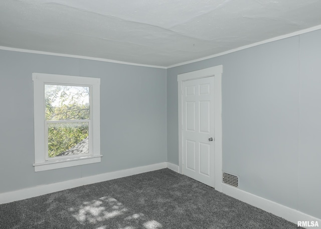 empty room featuring crown molding and dark colored carpet