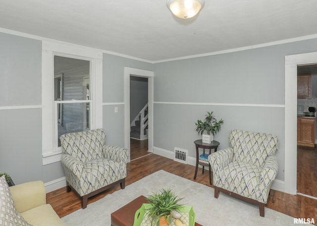 living area featuring crown molding and dark wood-type flooring