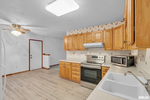 kitchen featuring stainless steel appliances, sink, a textured ceiling, and light hardwood / wood-style flooring