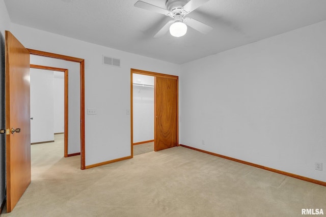 unfurnished bedroom featuring light colored carpet, a textured ceiling, ceiling fan, and a closet