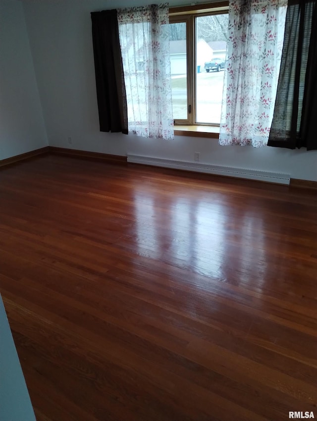 empty room featuring baseboard heating and dark hardwood / wood-style flooring