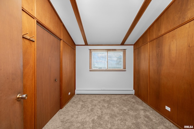 unfurnished bedroom with a baseboard radiator, vaulted ceiling with beams, and light colored carpet