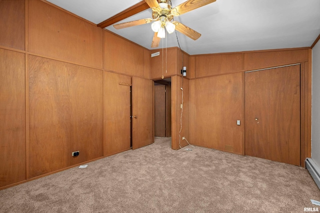 unfurnished bedroom featuring ceiling fan, light colored carpet, baseboard heating, and wood walls