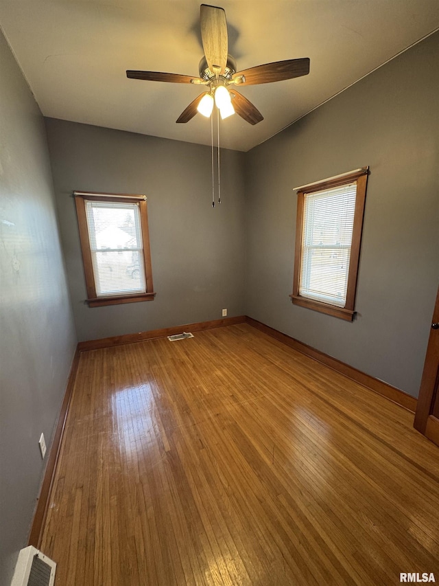 empty room featuring ceiling fan, plenty of natural light, and light hardwood / wood-style floors