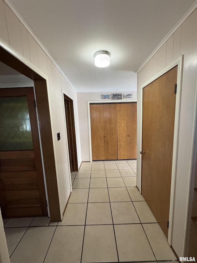 hall featuring light tile patterned floors and crown molding