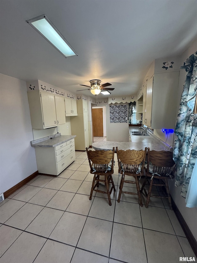 tiled dining area with ceiling fan and sink