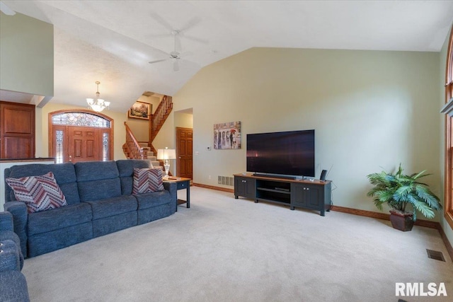 carpeted living room featuring ceiling fan with notable chandelier and high vaulted ceiling