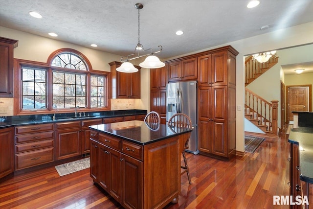 kitchen with a kitchen island, pendant lighting, sink, dark hardwood / wood-style flooring, and stainless steel refrigerator with ice dispenser