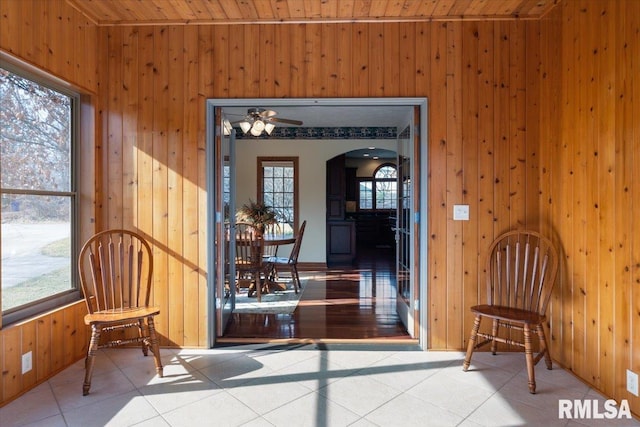 living area with wooden walls, wooden ceiling, and light tile patterned flooring