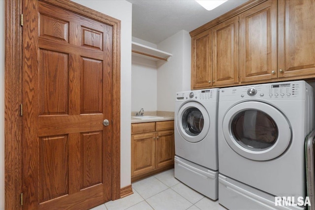 clothes washing area featuring cabinets, washer and clothes dryer, sink, and light tile patterned floors