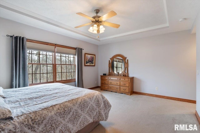 bedroom with light colored carpet, a raised ceiling, and ceiling fan