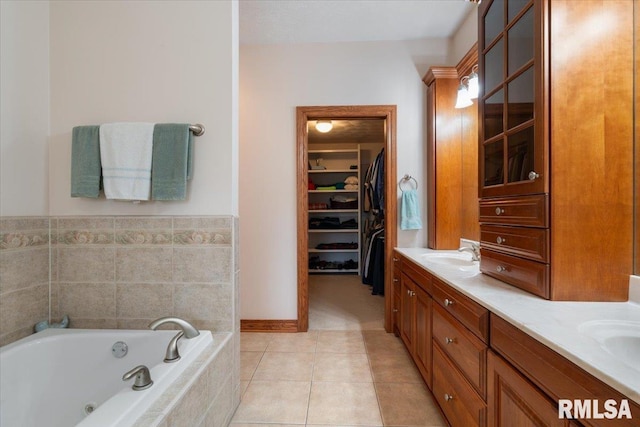 bathroom with tiled tub, vanity, and tile patterned floors