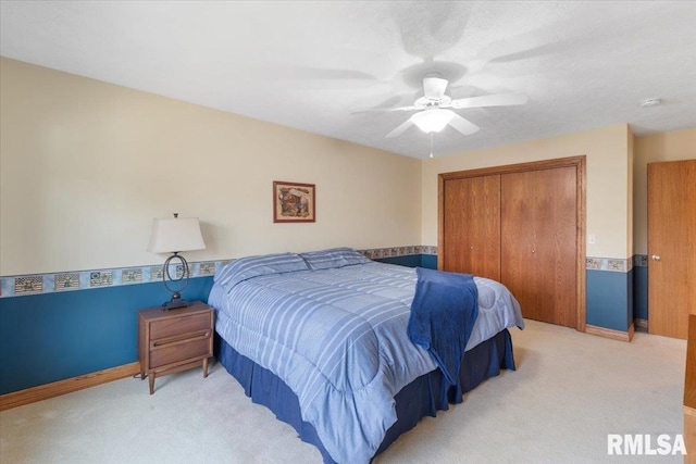 bedroom featuring ceiling fan, light carpet, and a closet