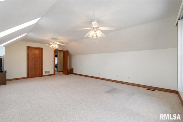 bonus room featuring lofted ceiling with skylight, carpet flooring, a wall mounted air conditioner, and ceiling fan