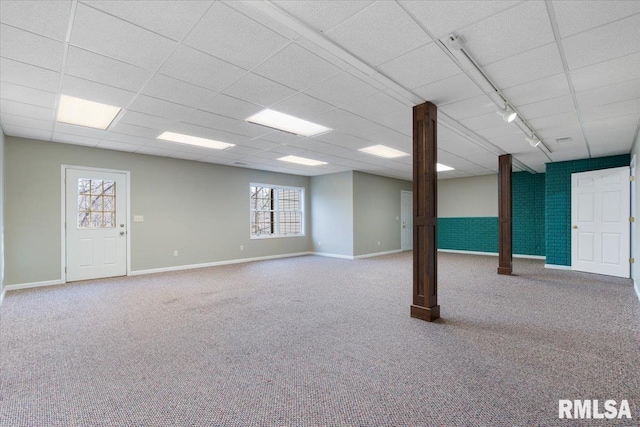 basement featuring a paneled ceiling, rail lighting, and carpet