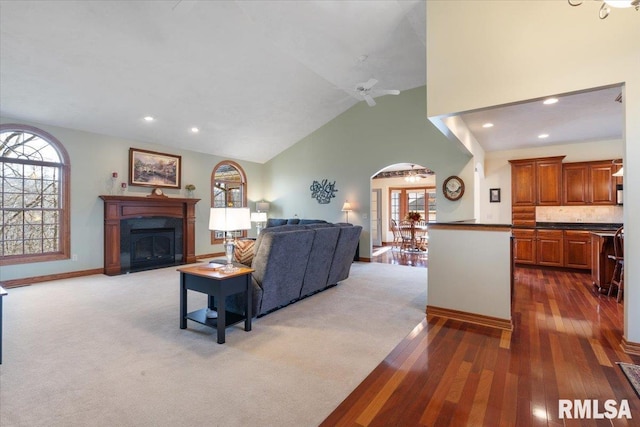 living room featuring ceiling fan, high vaulted ceiling, and dark carpet