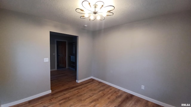 822 6th Ave S, Clinton, IA 52732 - unfurnished room featuring a notable chandelier, wood-type flooring, and a textured ceiling