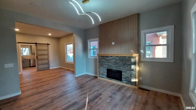 822 6th Ave S, Clinton, IA 52732 - unfurnished living room featuring a fireplace, a barn door, and hardwood / wood-style floors