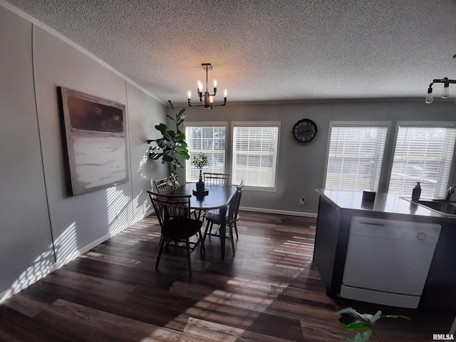 dining area featuring dark wood-type flooring, ornamental molding, an inviting chandelier, and a textured ceiling