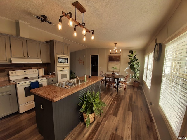 kitchen with pendant lighting, white appliances, gray cabinets, and a kitchen island