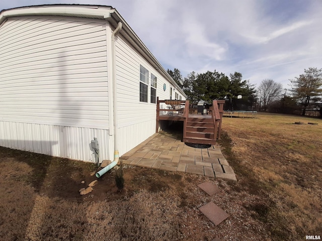 view of home's exterior featuring a trampoline, a wooden deck, and a patio