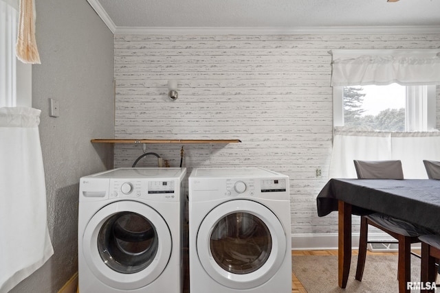 clothes washing area featuring crown molding, washing machine and clothes dryer, and light wood-type flooring