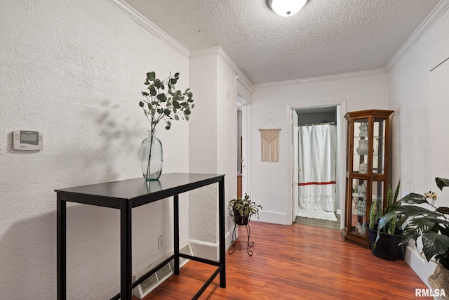 hall with crown molding, hardwood / wood-style floors, and a textured ceiling