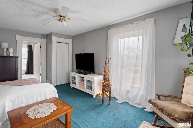 bedroom with ceiling fan, a closet, a textured ceiling, and dark colored carpet