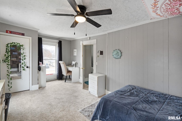 carpeted bedroom with ceiling fan, crown molding, wooden walls, and a textured ceiling